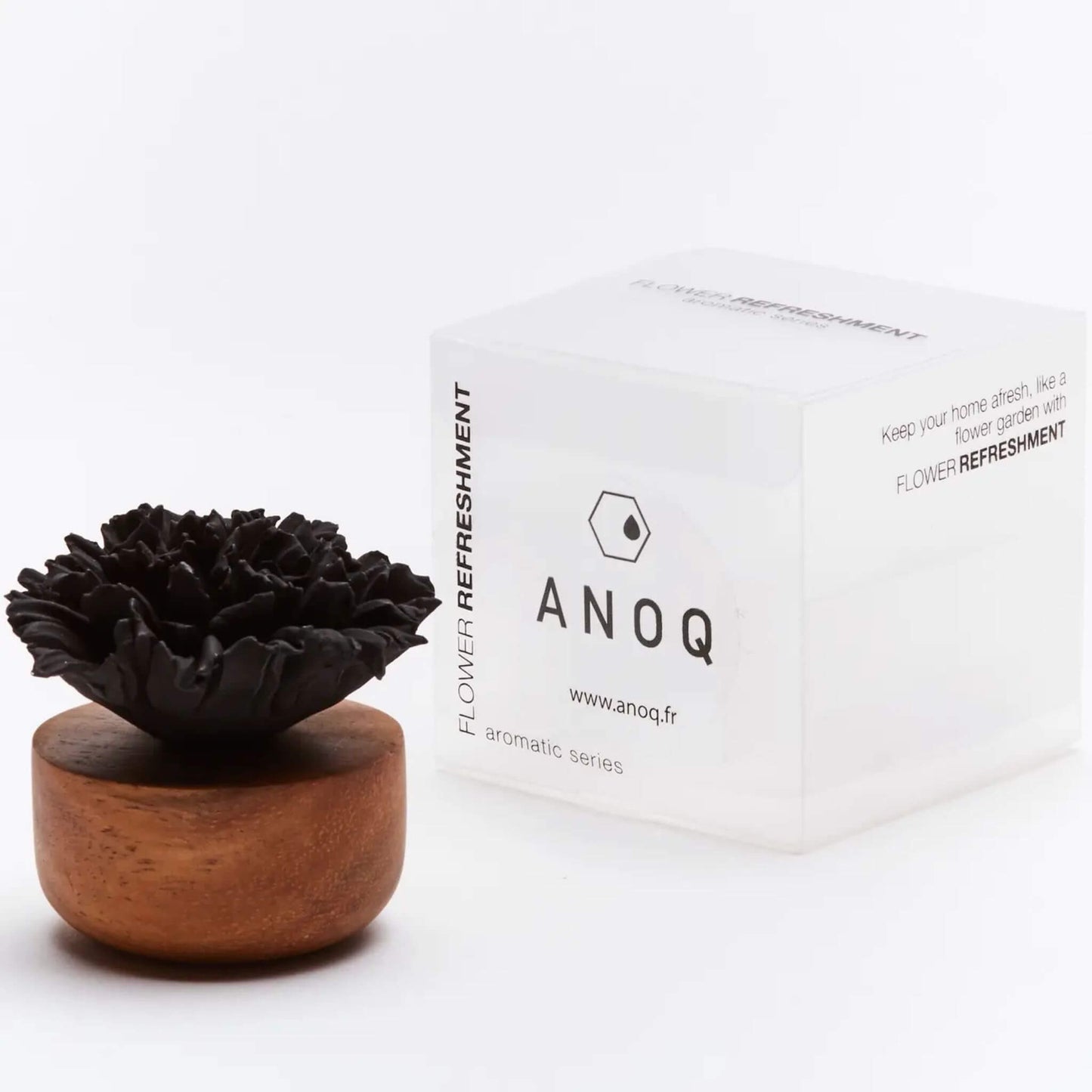 Schwarzer Blütendiffusor auf Holzsockel neben weißer Verpackung mit Anoq-Logo.
