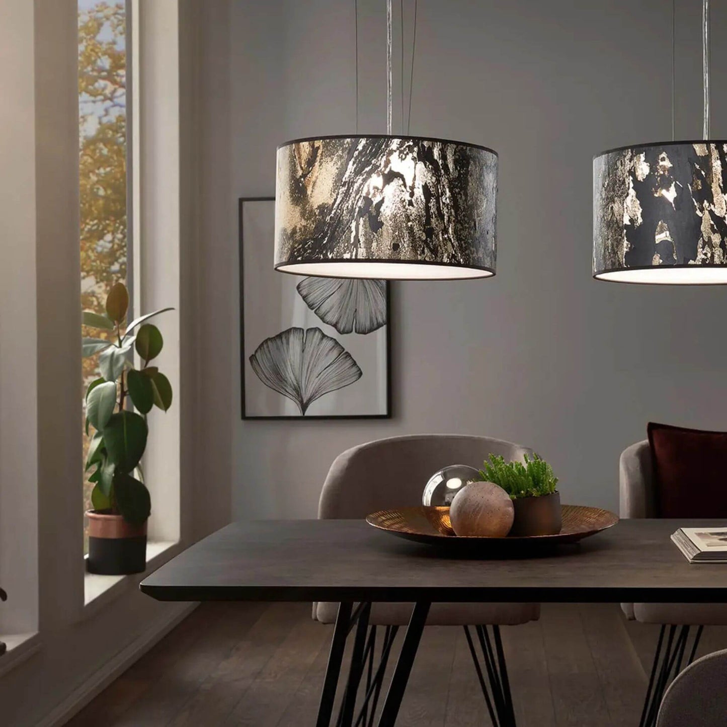 Zwei Pendelleuchten mit anthrazitfarbenen Schirmen in Schieferoptik beleuchten einen Esstisch in modernem Interieur.