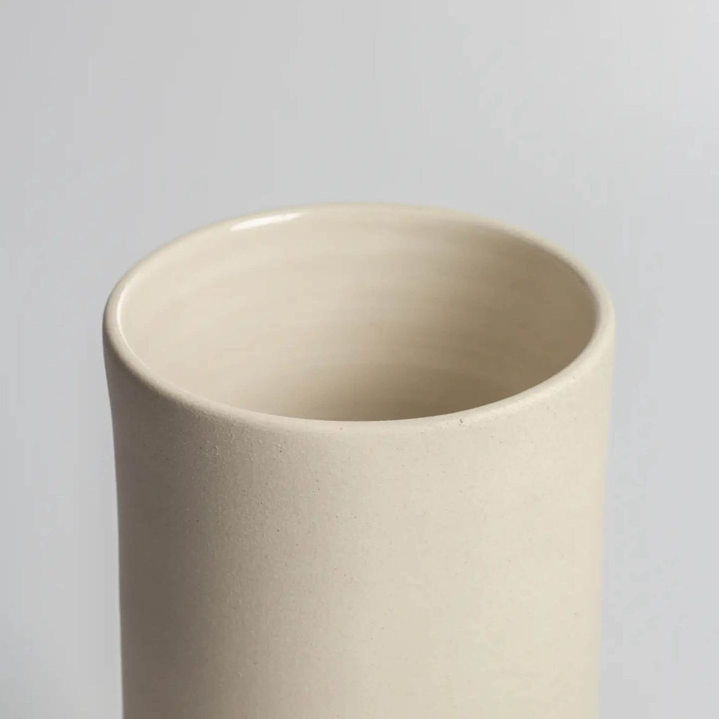 Detailansicht einer hohen Vase aus hellem Steingut mit runder Öffnung.