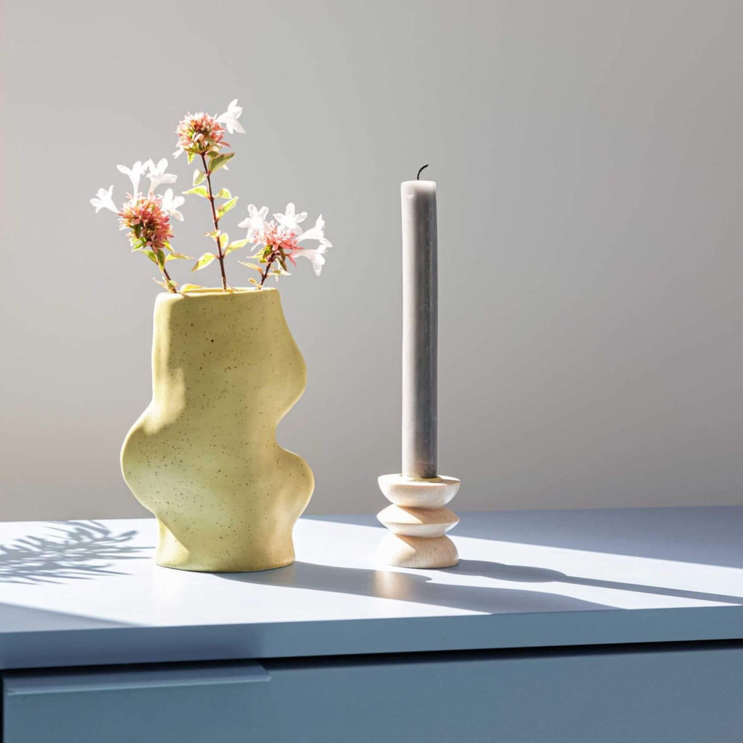 Vase mit Blüten neben Kerze