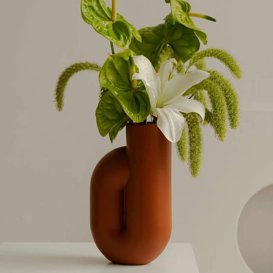 Terrakotta Vase mit Blumenarrangement auf Tisch.