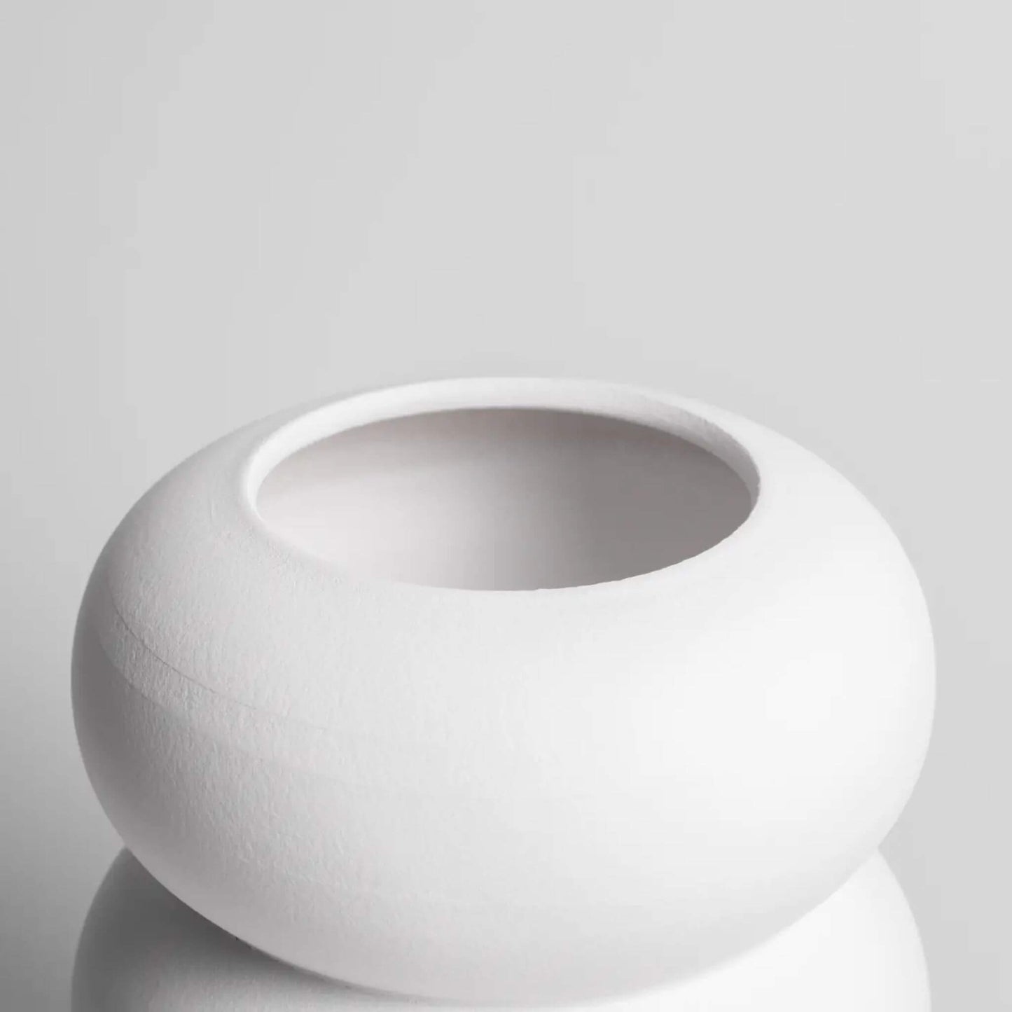 Detailansicht der weißen Vase mit runder Öffnung und geschwungener Form.