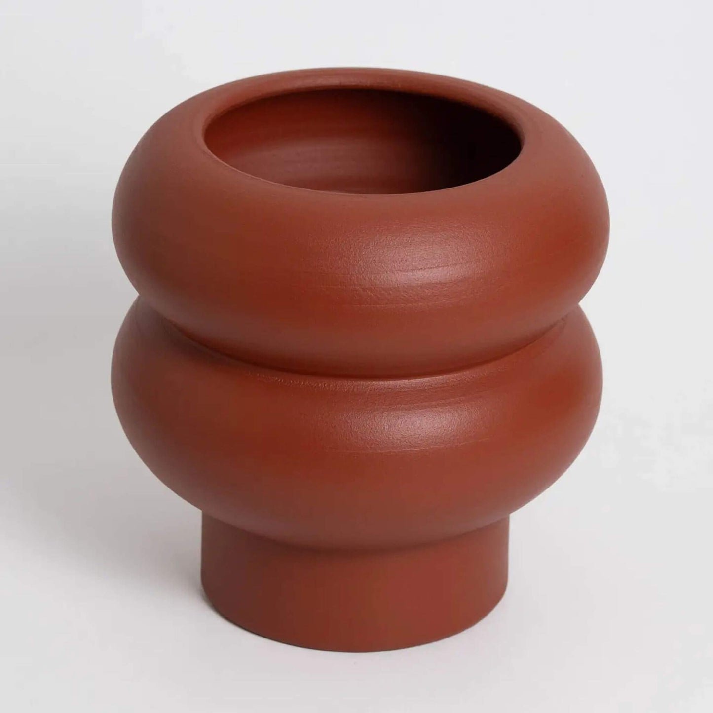 Kleine Terrakotta-Vase mit runder Form auf hellem Hintergrund.