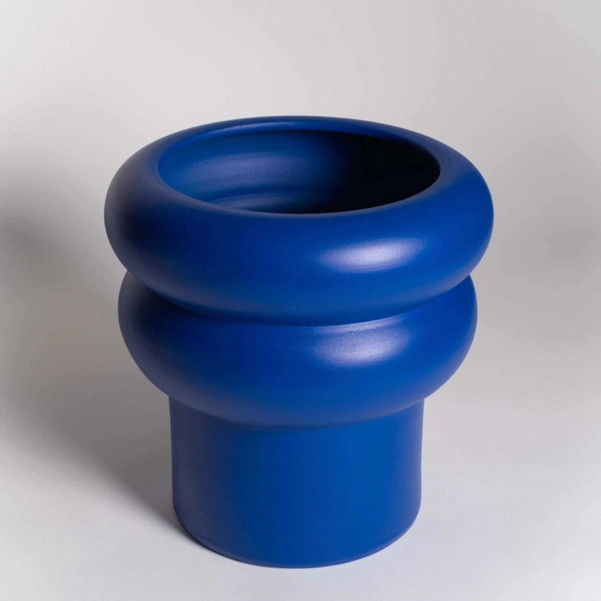 Leerer, großer Blumentopf in Blau mit markanter runder Wellenform.