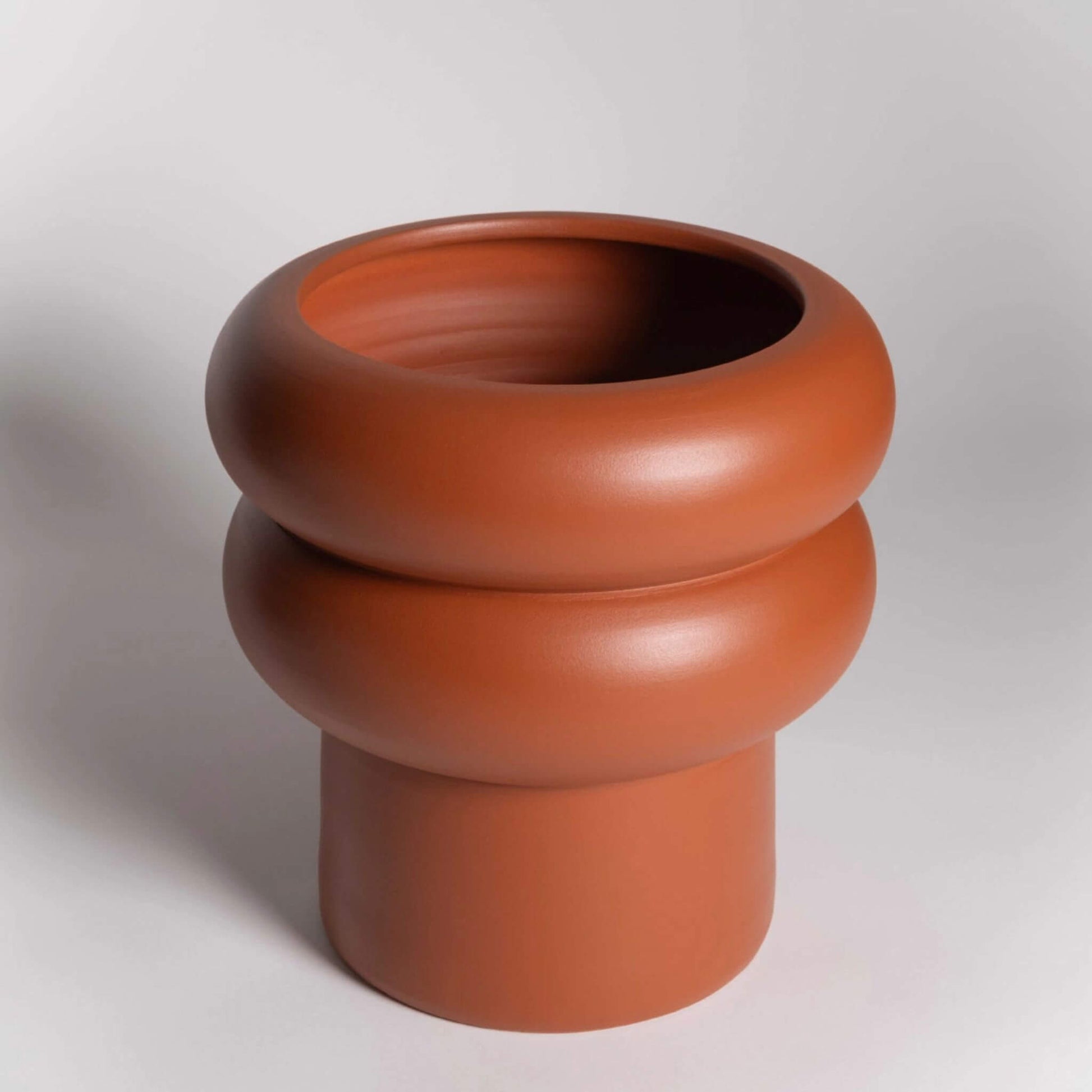 Leerer, großer Blumentopf in Terrakotta mit markanter runder Wellenform.