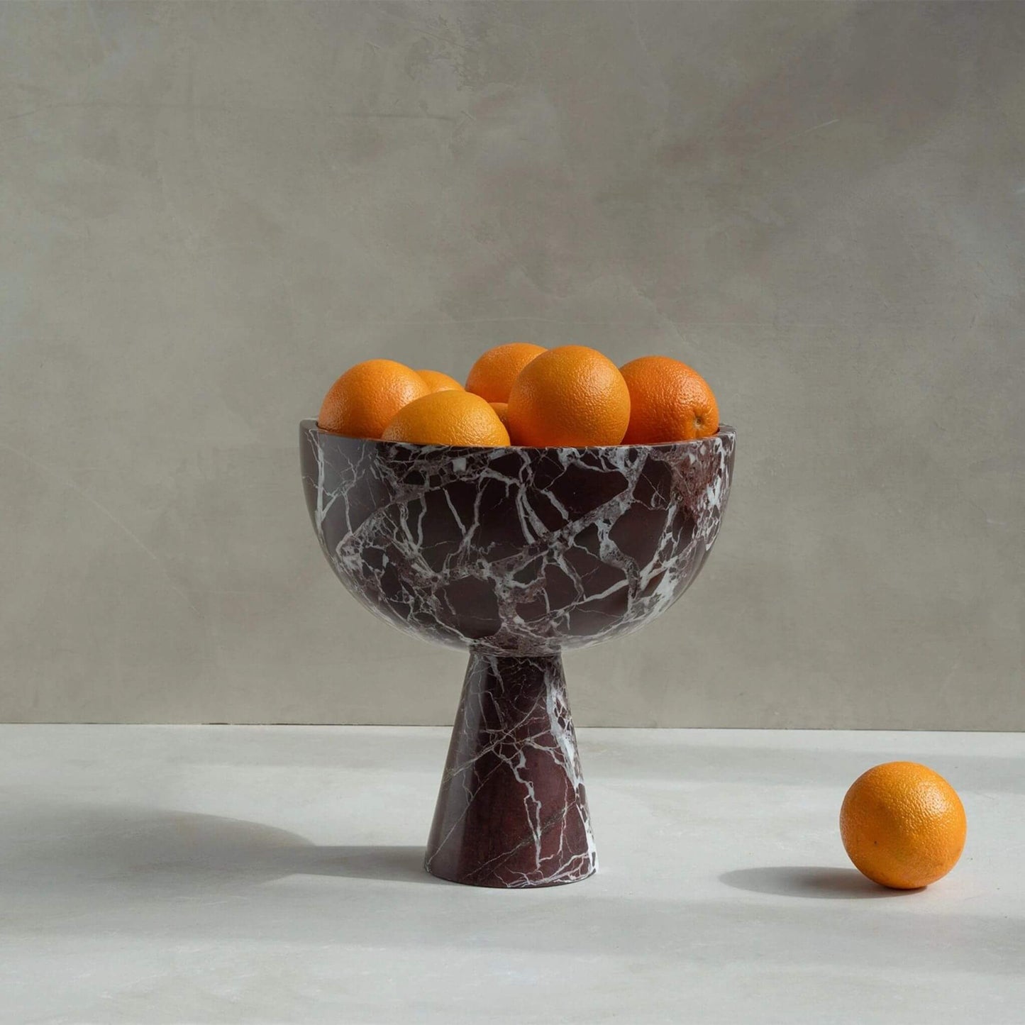 Große Standschale aus rotem Rosso-Levanto-Marmor mit weißen Adern, gefüllt mit Orangen auf hellem Steintisch.