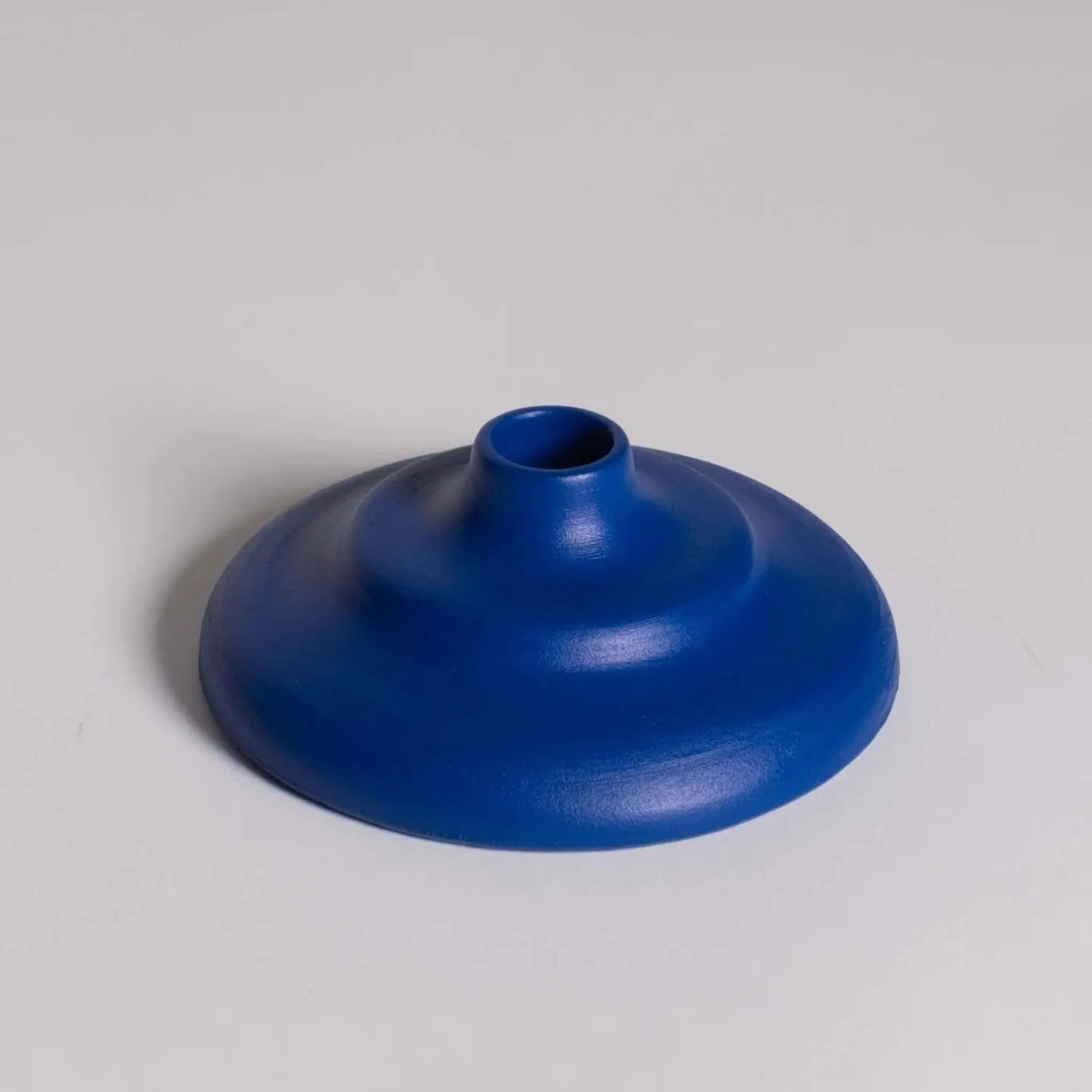 Runder, blauer Kerzenhalter mit abgestufter Form auf hellem Hintergrund.