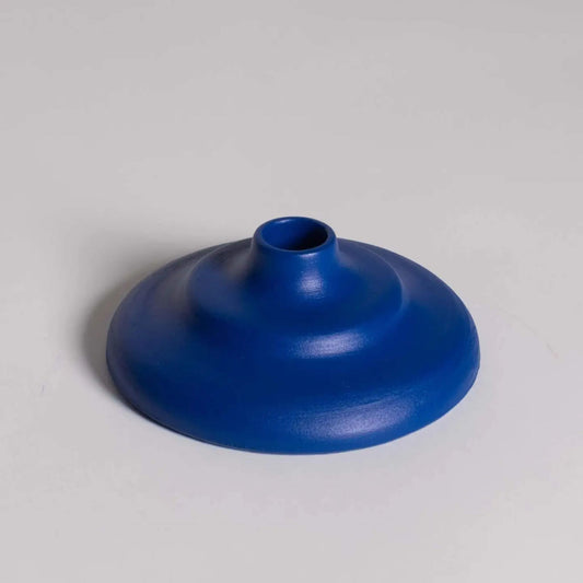 Runder, blauer Kerzenhalter mit abgestufter Form auf hellem Hintergrund.