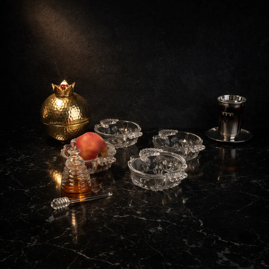 Goldene Granatapfel-Dose aus Aluminium auf schwarzem Marmortisch mit Honigglas, Apfel und Glasschalen in luxuriöser Tischszene.