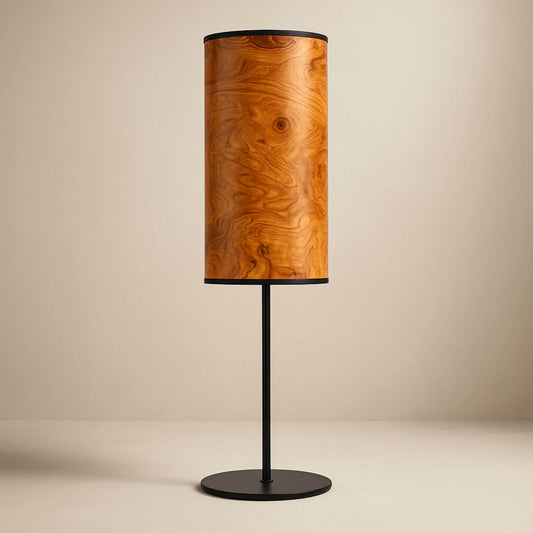 Tischlampe mit zylindrischem Holzfurnier-Schirm und schwarzem Standfuß vor weißem Hintergrund.