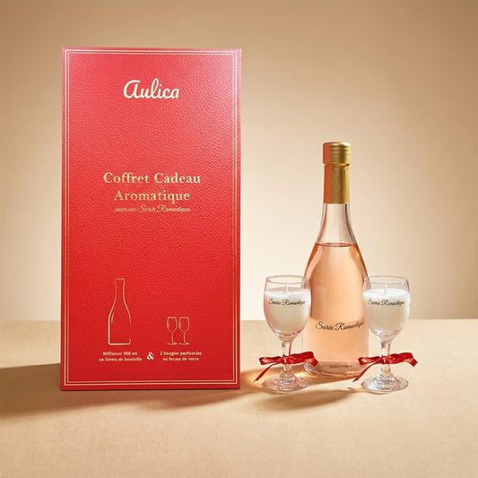 Aulica Geschenkbox Soirée Romantique in Rot mit Goldprägung, daneben Diffusor-Flasche und zwei Weinglas-Kerzen auf beigem Hintergrund