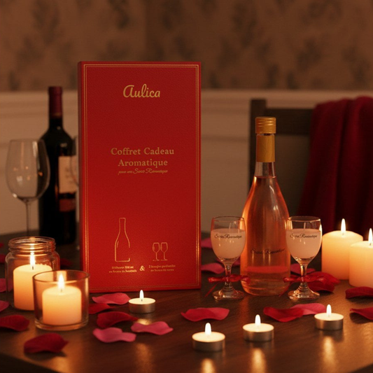 Aulica Soirée Romantique Geschenkset auf Tisch mit Rosenblättern, Teelichtern und Weingläsern, rote Aulica-Box im Hintergrund, warmes Kerzenlicht