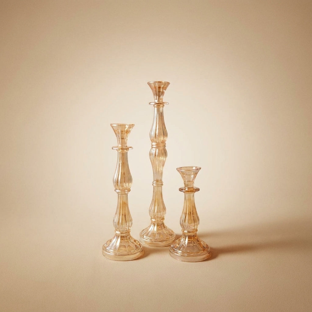 Drei Aulica Amber-Candlesticks in unterschiedlichen Höhen nebeneinander auf beigem Hintergrund, geripptes Bernsteinglas, klassische Kerzenhalter-Silhouette