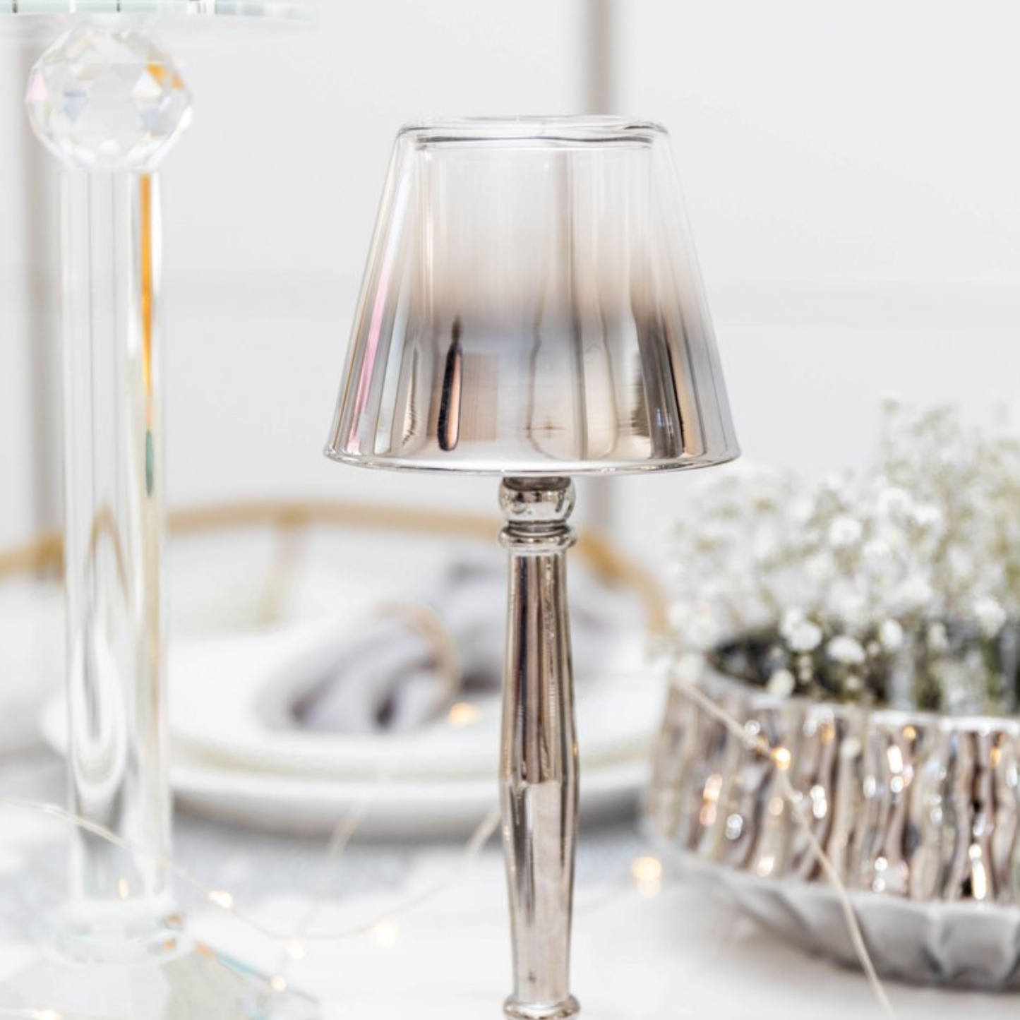 Aulica Silber-Lampenkerzenhalter ohne Teelicht auf gedecktem Tisch, Schleierkraut und Lichterkette im Hintergrund
