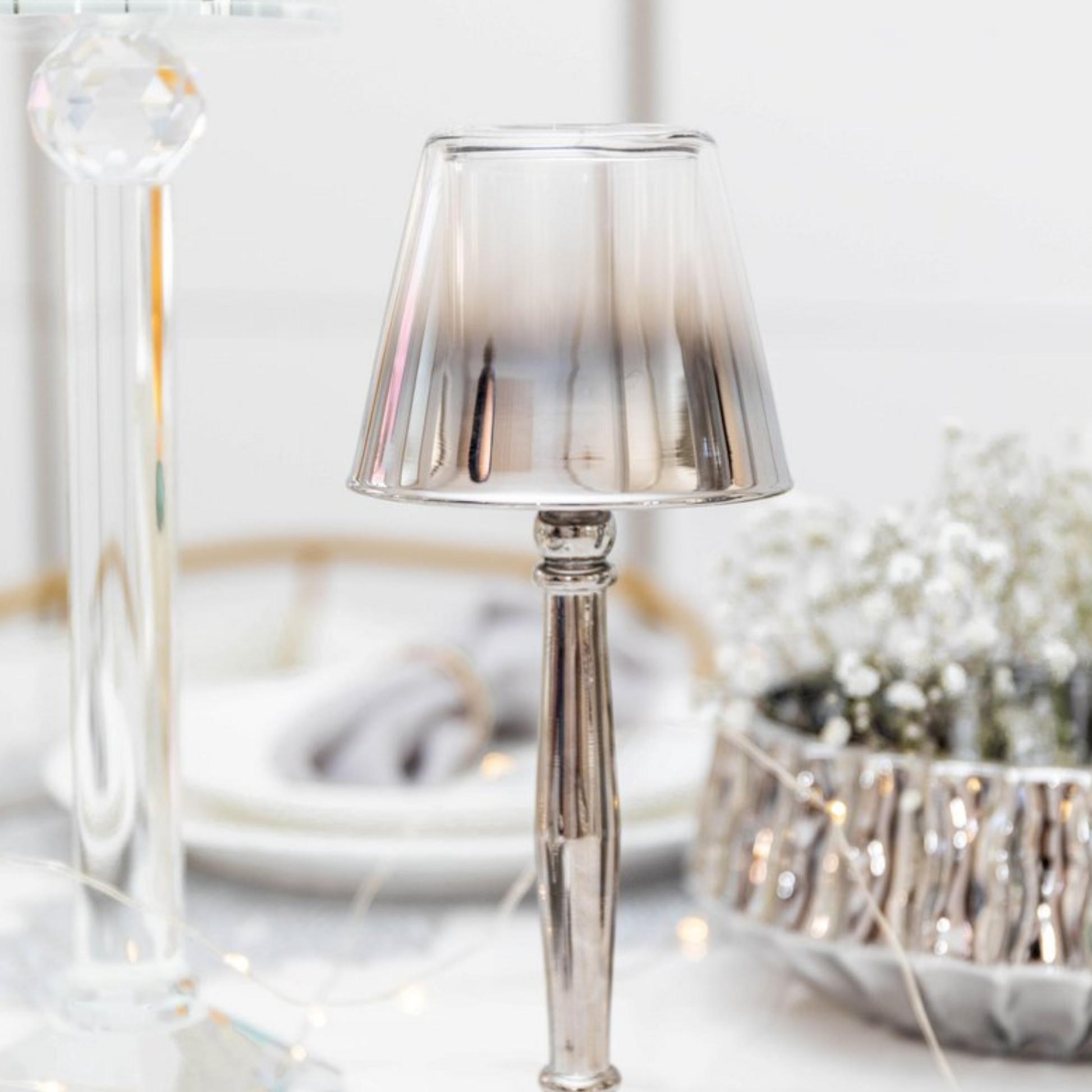 Aulica Silber-Lampenkerzenhalter ohne Teelicht auf gedecktem Tisch, Schleierkraut und Lichterkette im Hintergrund