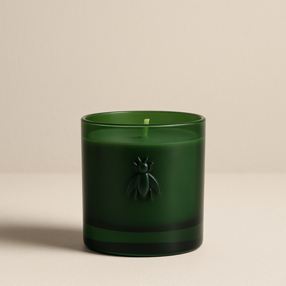 Grüne Duftkerze in schlichtem Glas mit geprägtem Bienensymbol, freigestellt auf weißem Hintergrund.