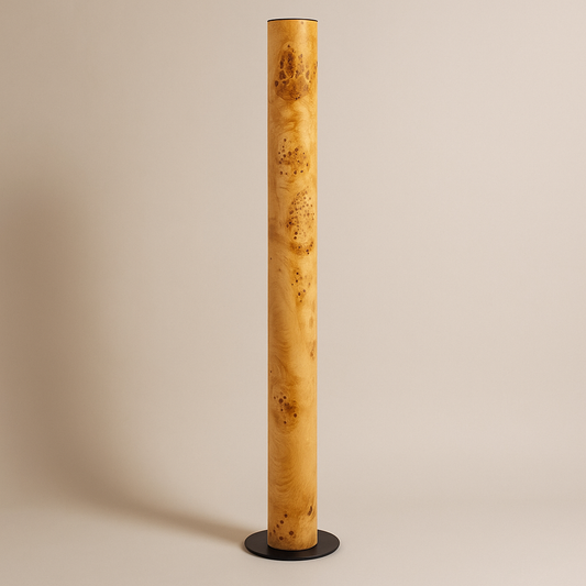 Zylindrische Stehlampe aus Maserholz mit natürlicher Maserung, auf rundem Metallsockel stehend, vor weißem Hintergrund.