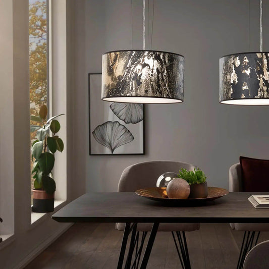 Zwei Pendelleuchten mit anthrazitfarbenen Schirmen in Schieferoptik beleuchten einen Esstisch in modernem Interieur.