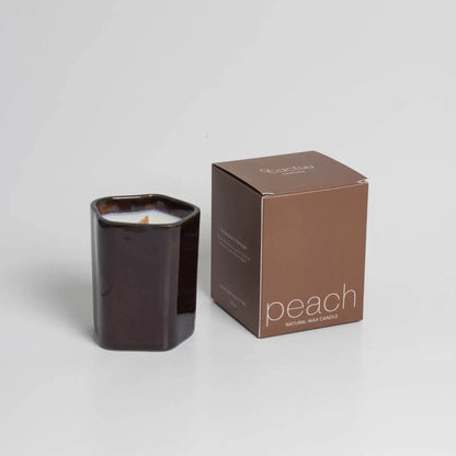 Dunkelbrauner Becher mit weißer Kerze, daneben eine braune Schachtel.