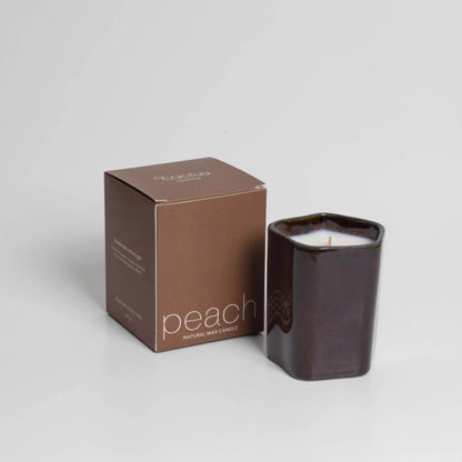 Dunkelbrauner Becher mit weißer Kerze und passender brauner Box daneben.