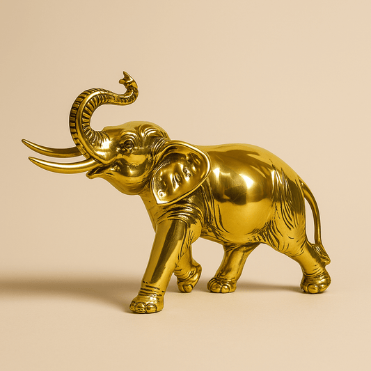 Glänzende goldene Elefantenfigur mit erhobenem Rüssel auf beige­farbenem Hintergrund.