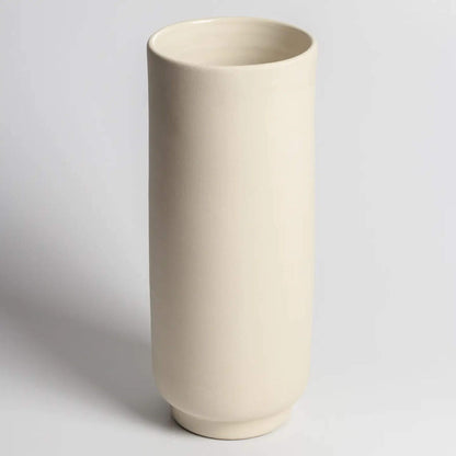 Hohe, zylindrische Vase aus hellem Steingut auf hellem Hintergrund.