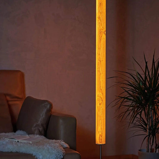 Leuchtende Stehlampe aus Eichenholz mit natürlicher Maserung, neben einem Ledersofa und einer Pflanze im Wohnzimmer.