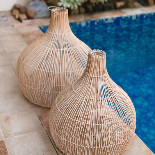 Zwei Rattan-Lampenschirme Alam in unterschiedlichen Größen am Poolrand arrangiert.