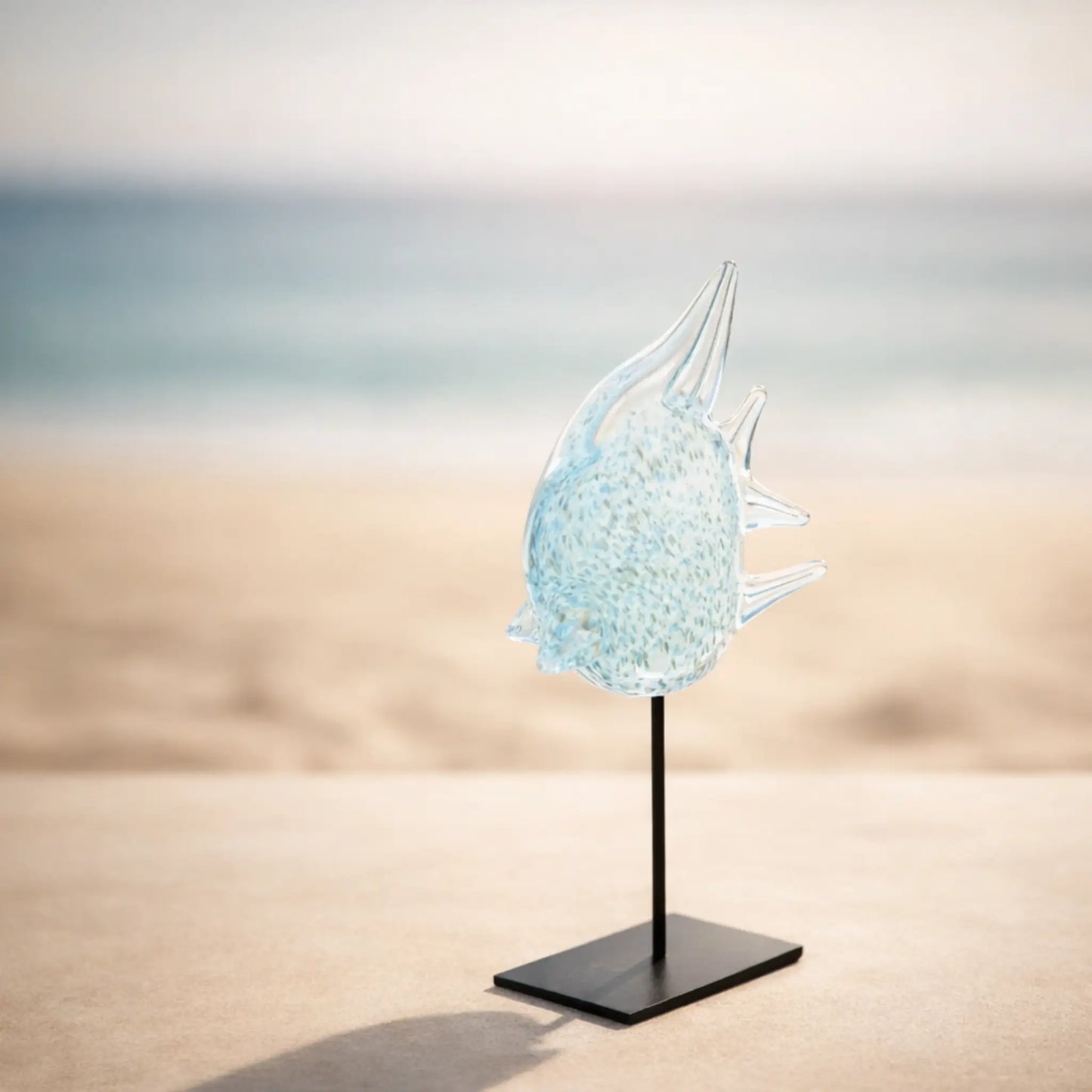 Blauer Glasfisch auf Metallständer am Strand dekoriert