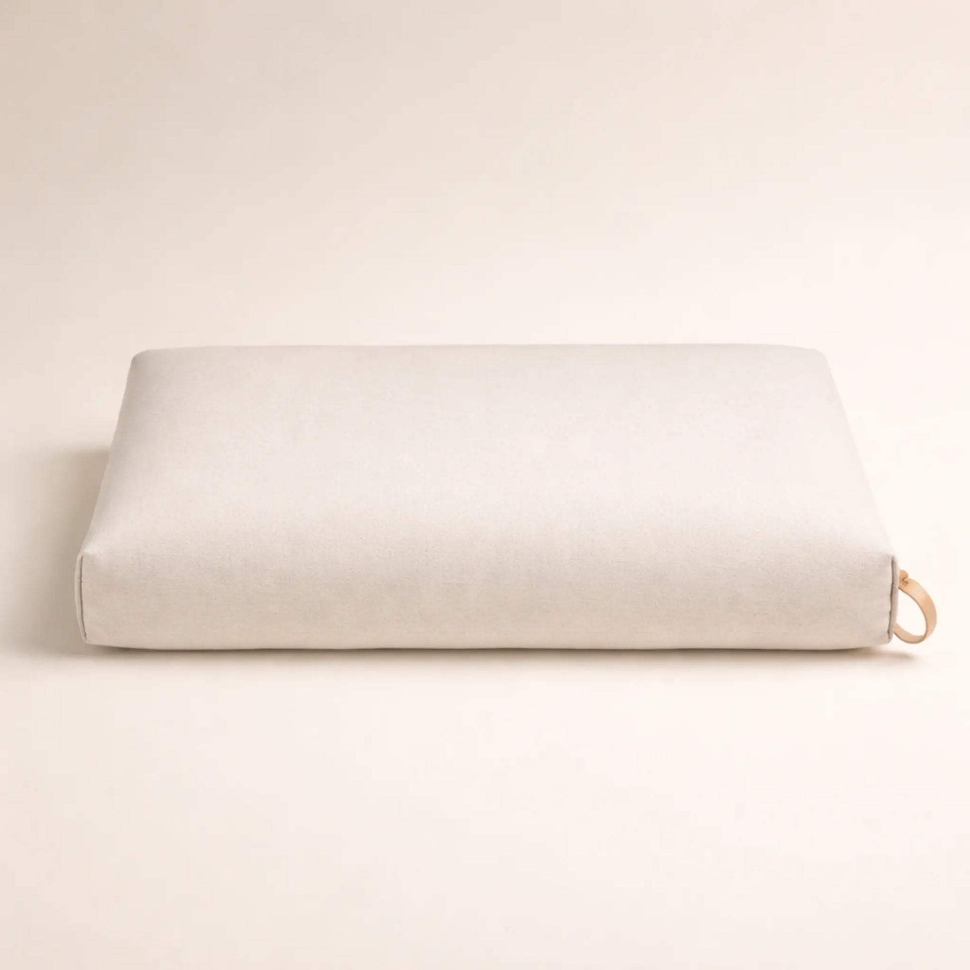 Rechteckiges Hundekissen in Beige aus geripptem Stoff, minimalistisch fotografiert vor hellem, neutralem Hintergrund.