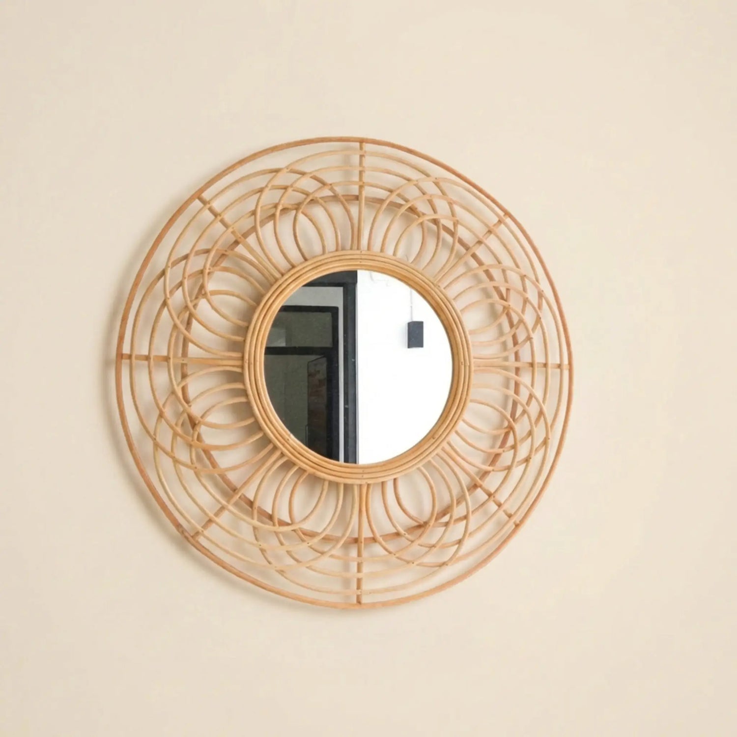 Handgefertigter runder Rattanspiegel Putuk an heller Wand